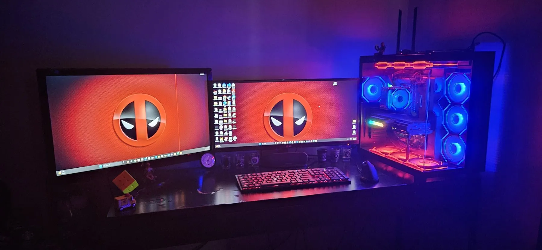 The full desk with dual monitors and the PC lit blue and red